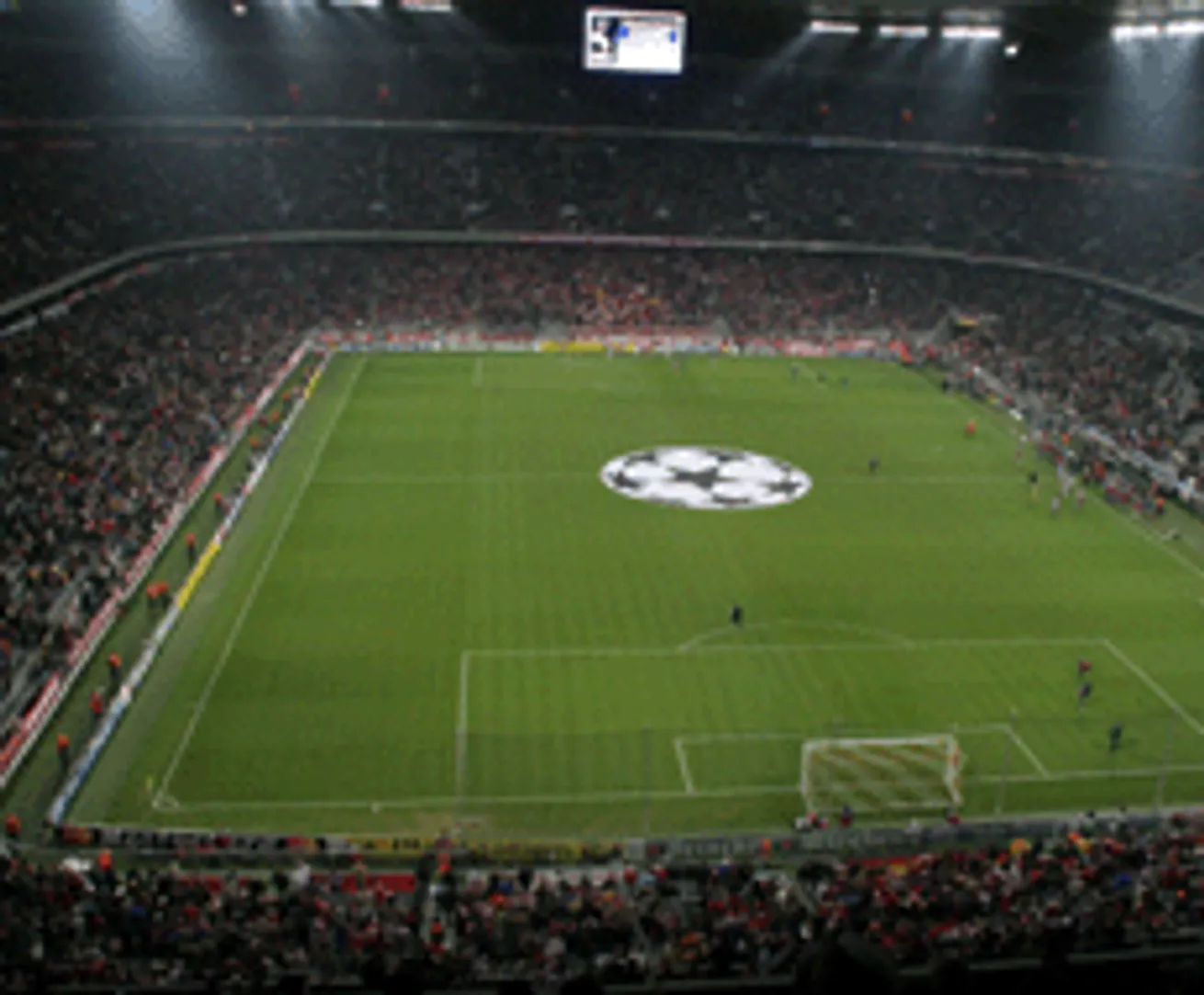 Een voetbalstadion met een grote afbeeldingsscherm en een logo in het midden van het veld.