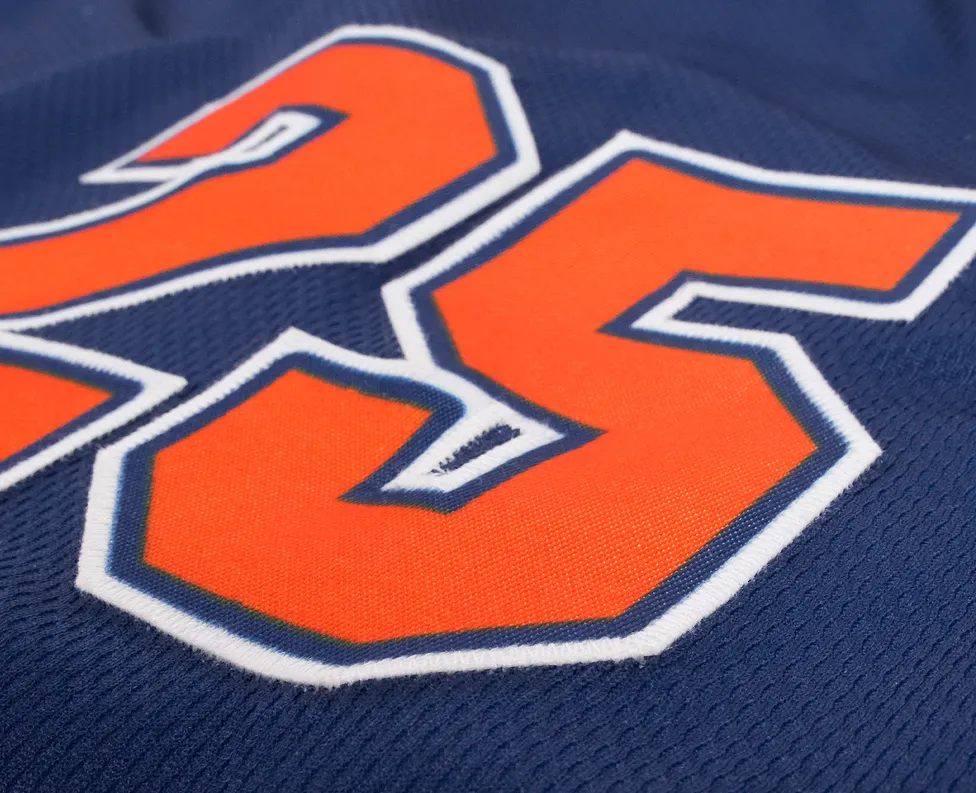 Close-up van een blauw sportshirt met het nummer 25 in feloranje.