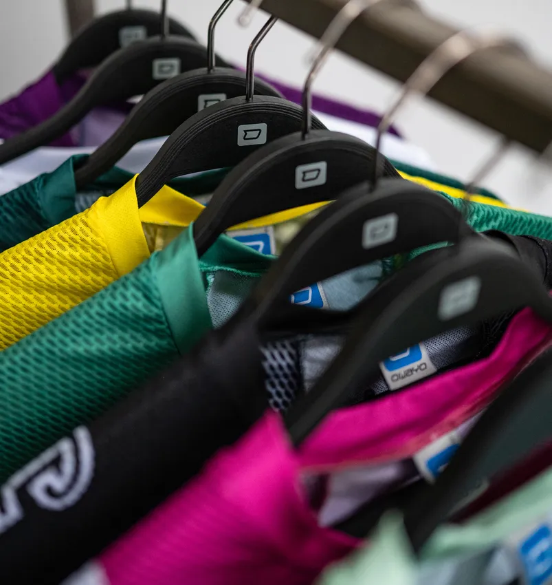 Meerdere kleurrijke, op maat gemaakte sportkleding hangt aan zwarte kledinghangers.