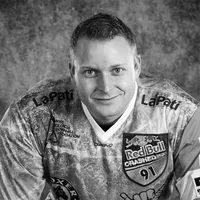 Een man in een sportief, gemusterd shirt met diverse sponsorlogos, waaronder Red Bull en LaPati, en de tekst 'owayo' op de borst.