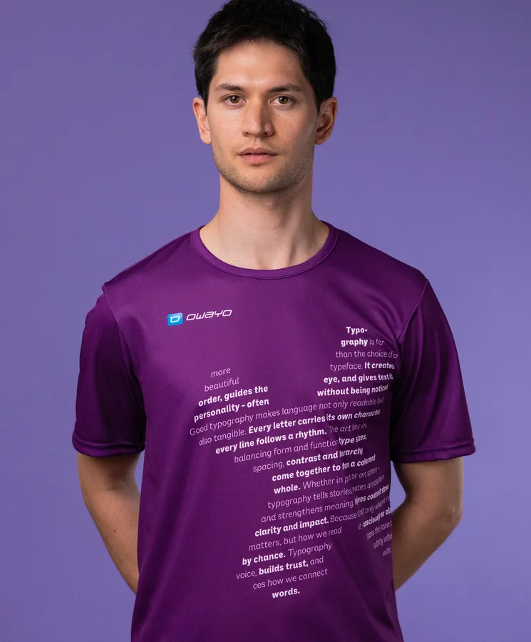 Een man draagt een paarse sportshirt met typografische tekst op de voorkant, tegen een paarse achtergrond.