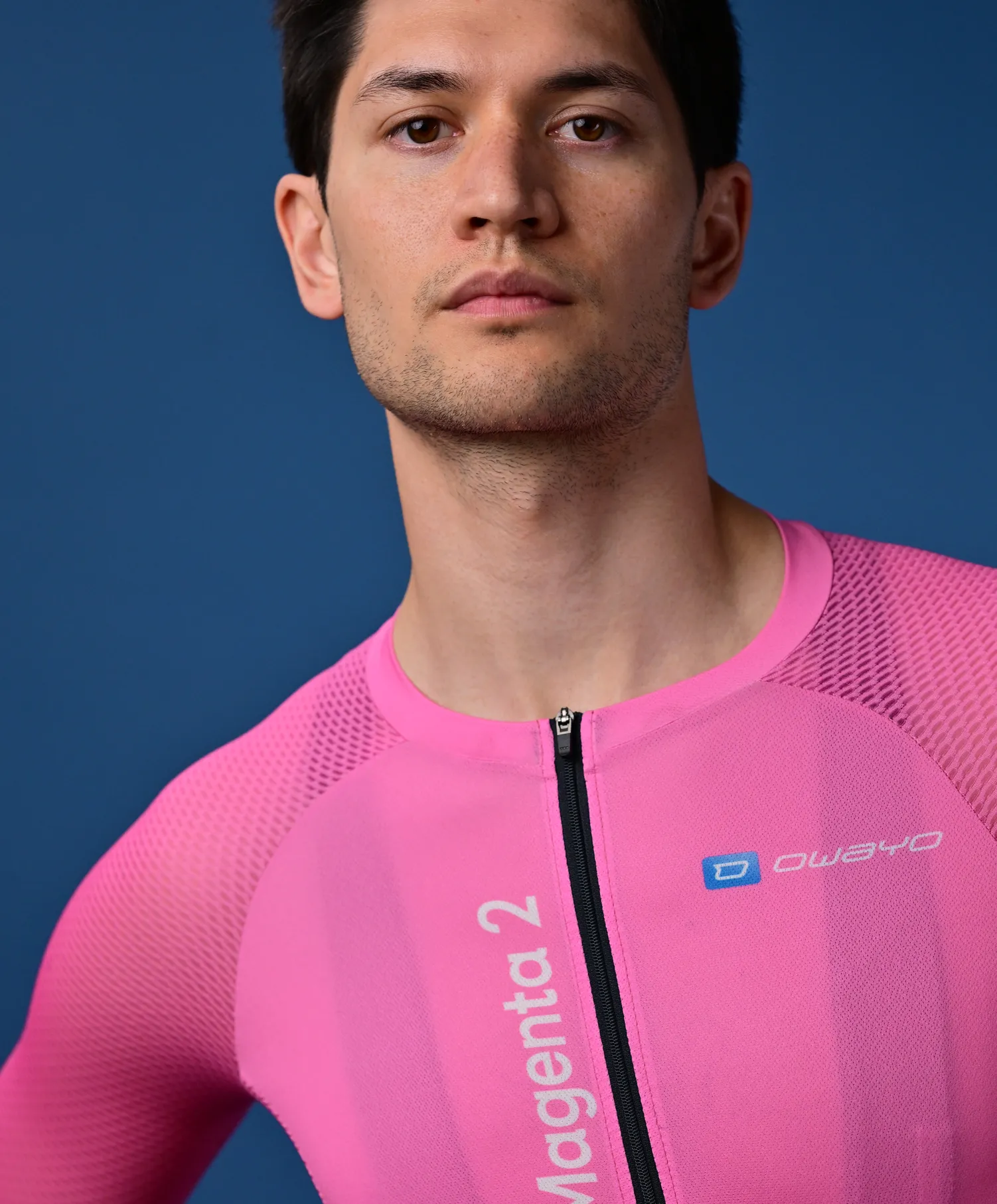 Een man draagt een roze, mouwloos sportshirt met rits en het 'owayo' logo op de borst.