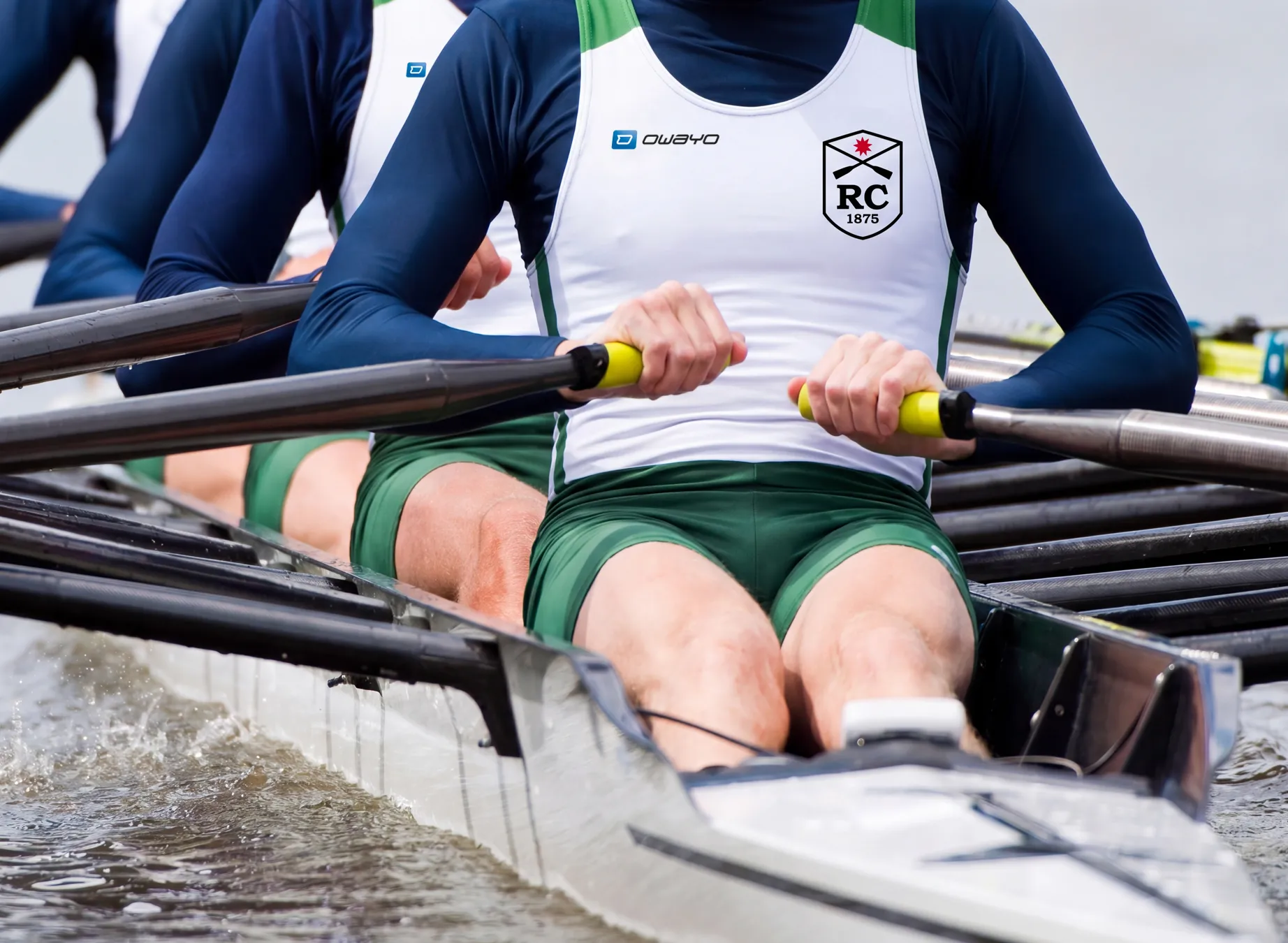 Drie roeiers in gepersonaliseerde sportkleding roeien synchroon in een boot.