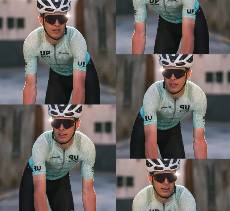 Een fietser in een aangepast lichtblauw tricot met het logo 'UP cycling' en 'owayo' op de borst, die op een straat fietst.