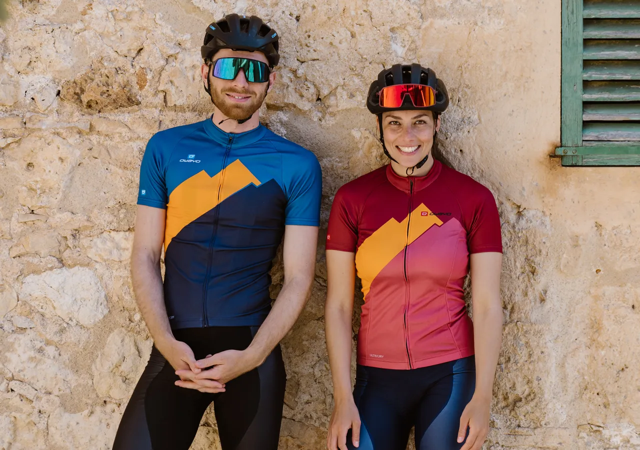 Een man en een vrouw in aangepaste sportkleding van owayo, staand voor een stenen muur.